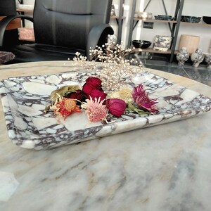 May include: A rectangular marble tray with a white and purple veined pattern. The tray holds dried flowers in shades of red, pink, and yellow. The tray is a decorative item, suitable for displaying small objects.