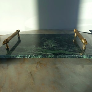 May include: A green marble serving tray with gold metal handles. The tray has a swirling pattern of green and white.