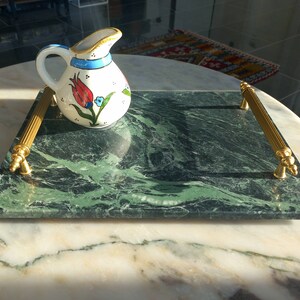 May include: A green marble serving tray with gold handles. The tray has a floral design and is ideal for serving snacks or drinks.