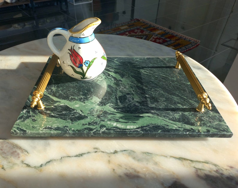 May include: A green marble serving tray with gold handles. The tray has a floral design and is ideal for serving snacks or drinks.