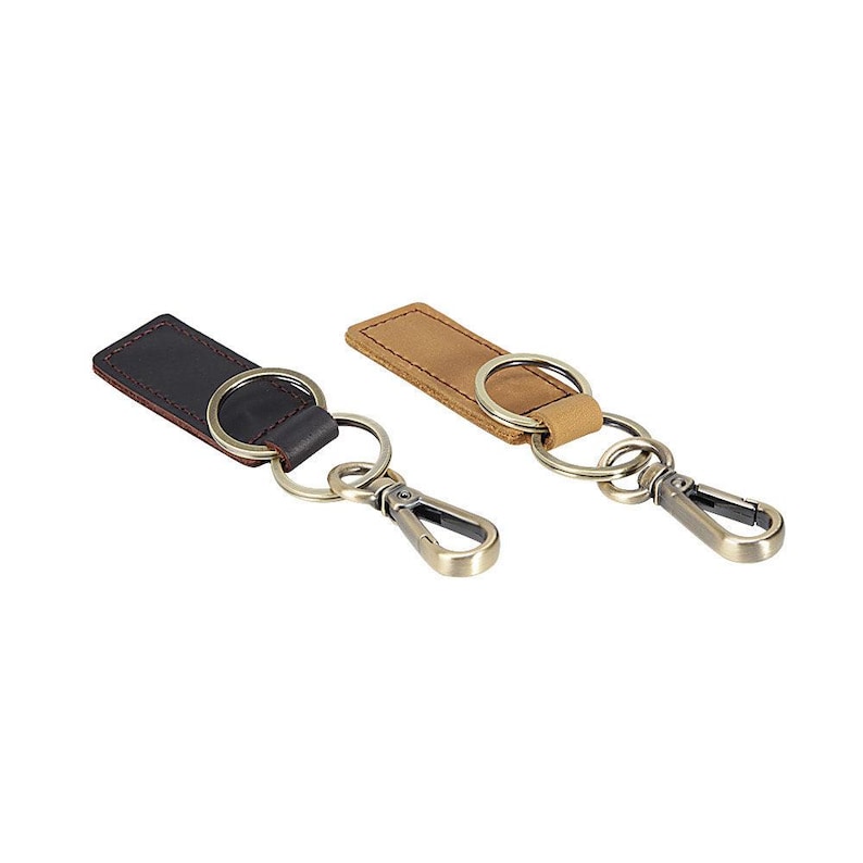 May include: Two leather keychains. One is dark brown with red stitching, the other is tan. Both have metal key rings and clasps. The keychains are on a white background.