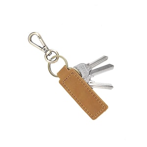 May include: A brown leather keychain with a rectangular tag and a metal clasp. Three silver keys are attached to the keychain. The keychain is designed for holding keys and is a practical accessory.