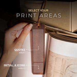 K&ouml;nnte beinhalten: Ein brauner Leder-Lesezeichen mit dem Text "SELECT YOUR PRINT AREAS". Das Lesezeichen hat zwei klare Bereiche mit der Aufschrift "QUOTES AREA 1" und "INITIAL & ICONS AREA 2". Das Lesezeichen wird &uuml;ber einem offenen Buch gehalten.
