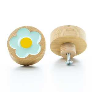 以下が含まれることがあります： 薄い青色の花柄が施された木製のノブが2つ。花の中心は黄色です。片方のノブは側面から見ており、銀色のネジが見えています。