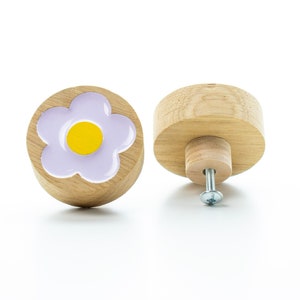 Op de afbeelding: Een houten knop met een paars bloemenontwerp en een geel centrum. De knop heeft een schroef aan de achterkant om te bevestigen aan een lade of kast.