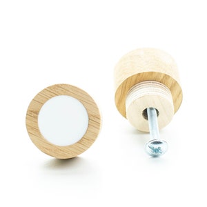 Könnte beinhalten: Zwei Holzknöpfe mit einem weißen Mittelkreis. Ein Knopf ist mit einer Schraube befestigt.
