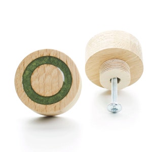 Può includere: Due pomelli per cassetti in legno con un design a cerchio verde. I pomelli sono rotondi e hanno una vite sul retro.
