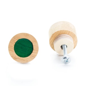 Op de afbeelding: Twee houten knoppen voor lades met een groene hars inlay. Eén knop is van de zijkant te zien, waarbij de schroefbevestiging zichtbaar is. De andere knop is van de voorkant te zien.