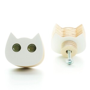 以下が含まれることがあります： 緑色の目をした白い木製の猫の形をした引き出しの取っ手。銀色のネジが付いています。