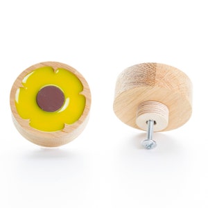 Op de afbeelding: Twee houten kastknoppen met een geel bloemetjesontwerp. De ene knop is van voren te zien en de andere van achteren, met de schroef zichtbaar.
