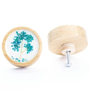 May include: A round wooden knob with a clear resin insert featuring a pressed blue flower. The knob has a silver screw for attaching to a drawer or cabinet.