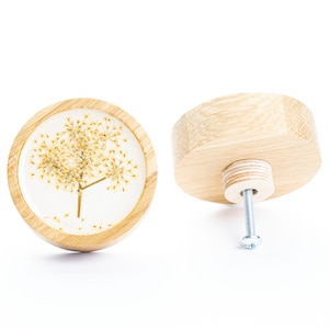 Op de afbeelding: Een ronde houten knop met een transparante harsinzet met een gedroogde bloem. De knop heeft een zilveren schroef om te bevestigen aan een lade of deur.