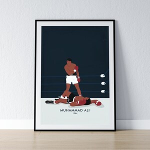 May include: A black and white illustration of boxer Muhammad Ali standing over a fallen opponent in a boxing ring. The text "Muhammad Ali 1964" is below the image.