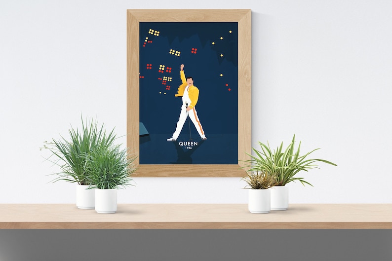 May include: A framed poster with a blue background featuring a cartoon illustration of a person in a yellow jacket and white pants with a microphone. The person is standing with their arm raised in the air. The text "QUEEN 1986" is at the bottom of the poster.