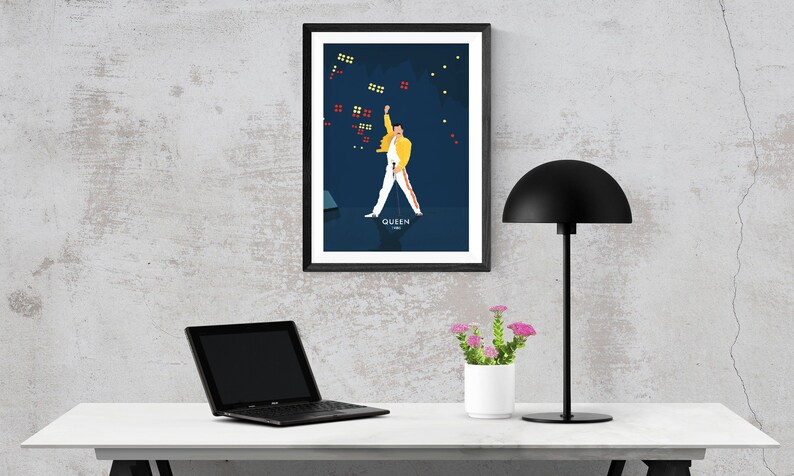 May include: A framed poster of a man in a yellow jacket and white pants, with a microphone in his hand, performing on stage. The poster has a blue background with white stars and the word "QUEEN" at the bottom.