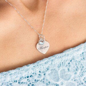 May include: A silver necklace with a heart pendant that says "Harper" and a small blue gemstone.