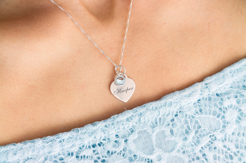 May include: A silver necklace with a heart pendant that says "Harper" and a small blue gemstone.