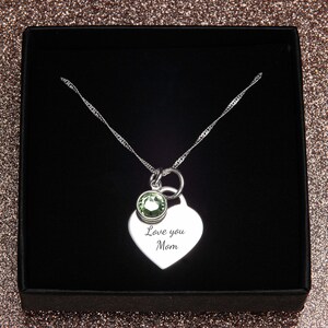 May include: Silver necklace with a heart pendant that says "Love you Mom" and a small green gemstone. The necklace is in a black box.