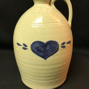 May include: A white ceramic pitcher with a blue heart design and the words "Pinewood Pottery" stamped on the side.