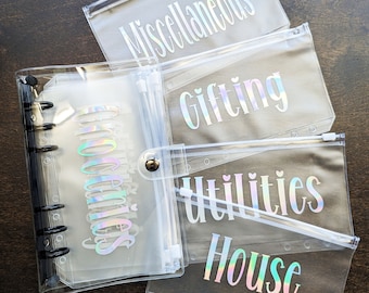 May include: Four clear plastic zippered pouches with iridescent labels. The labels read "Miscellaneous", "Gifting", "Utilities", and "House".