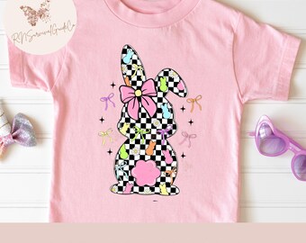 May include: Pink t-shirt featuring a checkered bunny design with a pink bow, colorful Easter eggs, and bows. The text "DIGITAL DOWNLOAD | PNG" is at the bottom. A cute and colorful design for Easter.