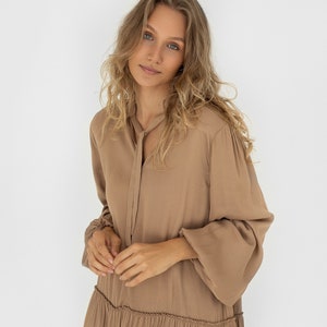 Sandstone loose silhouette dress with tie neckline. Dress has a dropped shoulder line, balloon sleeves anda ruffle at the bottom. image 1