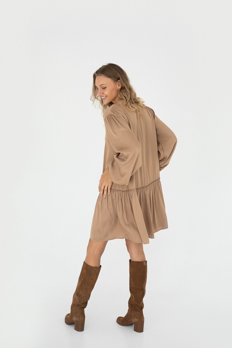 Sandstone loose silhouette dress with tie neckline. Dress has a dropped shoulder line, balloon sleeves anda ruffle at the bottom. image 4