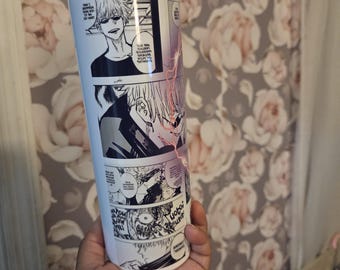 May include: A white cylindrical tumbler featuring a black and white manga-style graphic print of a character with spiky hair and sunglasses. The design includes multiple comic panels with speech bubbles and a thin, vertical red lightning bolt graphic.