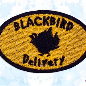 May include: Embroidered patch with a yellow oval background and black border. The patch features the words "BLACKBIRD Delivery" in black, with a blackbird silhouette in the centre. The patch is designed for clothing or accessories.