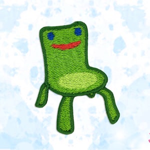 May include: Embroidered patch depicting a green chair with a smiling face, blue eyes, and a red mouth. The chair has four legs and is set against a light blue and white watercolour background. The patch is designed for clothing or accessories.