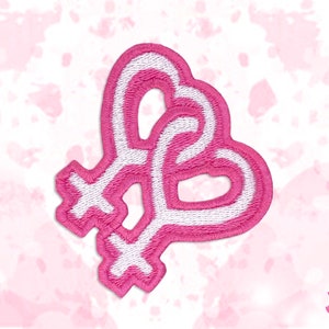 May include: A pink and white embroidered patch featuring two intertwined Venus symbols, forming a heart shape. The patch has a white outline and is set against a soft pink background with a watercolor effect. The patch is a symbol of lesbian pride.
