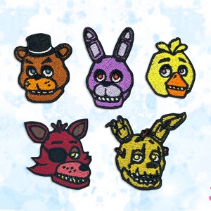 Peut inclure: Ensemble de cinq écussons brodés représentant des personnages d'un jeu vidéo populaire. Les écussons incluent un ours brun avec un chapeau noir, un lapin violet, un poussin jaune, un renard rouge avec un cache-œil et un personnage jaune-vert.