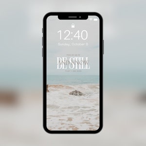 May include: A phone screen displaying a calming beach scene with the text "Be Still and Know That I Am God" and the Bible verse "Psalm 46:10".