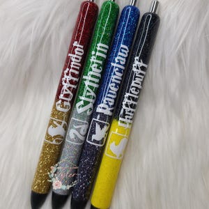 May include: Four glitter pens with different colored glitter and house names from the Harry Potter series: Gryffindor, Slytherin, Ravenclaw, and Hufflepuff.