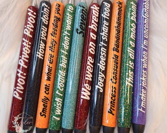 Op de afbeelding: Tien glitterpennen in verschillende kleuren met verschillende zinnen erop gedrukt, waaronder "Pivot! Pivot! Pivot!" en "Hoe gaat het?"