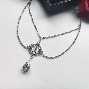 May include: Silver head chain with an ornate central design and a dangling teardrop pendant. The chain features delicate links and an intricate filigree pattern, ideal for adding a touch of elegance.