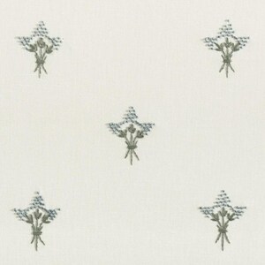 May include: Cream-colored fabric with a repeating pattern of embroidered floral bouquets. Each bouquet features blue-gray flowers and green stems, tied with a green ribbon. The design is evenly spaced across the fabric.