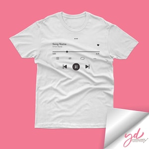 Op de afbeelding: Wit T-shirt met een muziekspeler-afbeelding. De afbeelding toont een songtitel, artiestennaam, afspeelbesturingselementen en een voortgangsbalk.