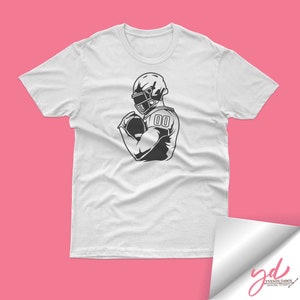 May include: White t-shirt with a black and white illustration of a football player wearing a helmet and holding a football. The player's jersey has the number "00" on it.