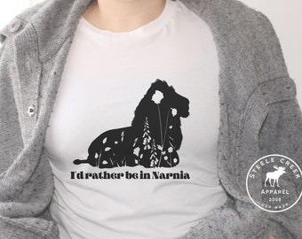 May include: White t-shirt with a black silhouette of a lion with flowers and the text "I'd rather be in Narnia". The shirt also has a black and white logo with the text "Steele Creek Apparel 2008 USA Made".