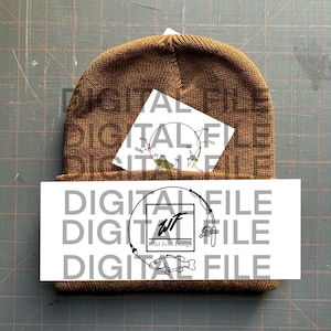 Może przedstawiać: Brązowa wełniana czapka z białym naklejonym obrazkiem przedstawiającym wędkę i rybę. Naklejka zawiera również tekst "Wild Fern Design" i inicjały "WF". Naklejka jest umieszczona z przodu czapki.