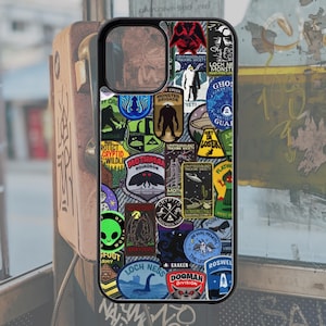 May include: Black phone case featuring a collage of patches with cryptid and paranormal themes. Patches include images of Bigfoot, the Loch Ness Monster, Mothman, and UFOs. The case has a black border and a cutout for the camera.