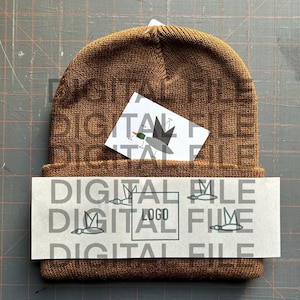 May include: A brown knit beanie with a white card that says "DIGITAL FILE" and has a small graphic of a bird on it. The card is tucked into the beanie's fold.