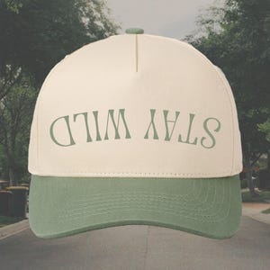 May include: A beige and green baseball cap with the text "STAY WILD" in green lettering.