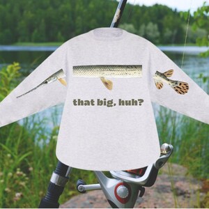 May include: A light gray long-sleeve shirt with a fish design. The shirt features a fish scale pattern and the text "that big, huh?" in a dark green color. The design includes fish parts on the sleeves.