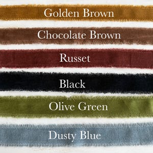 May include: A selection of velvet ribbons in various colors, including golden brown, chocolate brown, russet, black, olive green, and dusty blue. Each ribbon has a frayed edge and is labeled with its color name in white text.