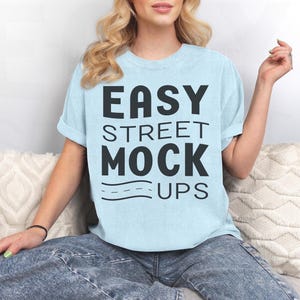 May include: A light blue t-shirt with the text "EASY STREET MOCK UPS" printed in black.