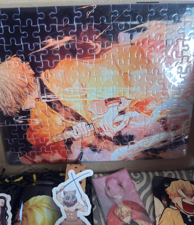May include: A partially assembled jigsaw puzzle featuring a character with yellow hair and a sword, set against a fiery orange and yellow background. The puzzle is in a box with other character-themed merchandise.
