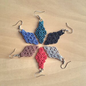 Puede incluir: Seis pares de pendientes hechos a mano con forma de diamante y diseños intrincados de nudos. Los pendientes están disponibles en turquesa, negro, marrón claro, rojo, gris y azul.