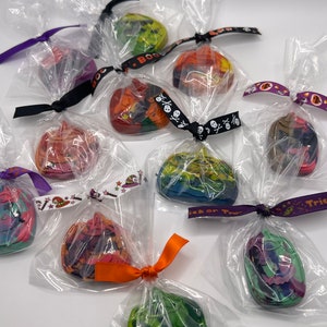 K&ouml;nnte beinhalten: Sortiment an bunten Halloween-Kreiden in Form von K&uuml;rbissen, einzeln verpackt in durchsichtigen Plastikt&uuml;ten mit festlichen B&auml;ndern.
